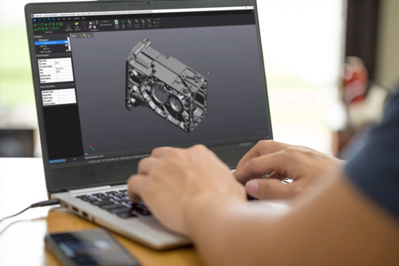 Close-up of someone working on a laptop displaying a grey automotive differential housing CAD file
