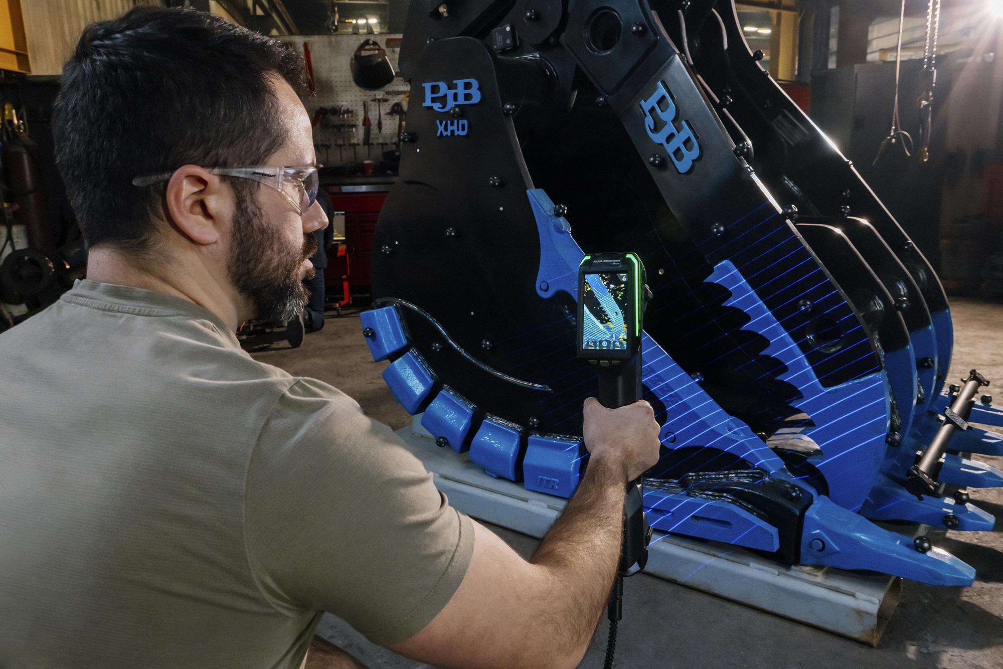 A user scanning a gripper component with the HandySCAN MAX EVO 3D scanner, with the live scan displayed on the scanner’s embedded screen.