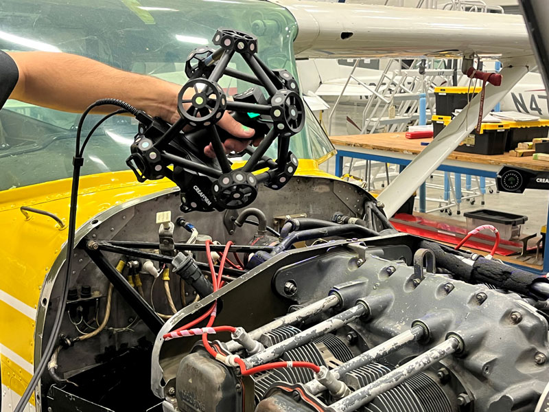 A technician holds the MetraSCAN BLACK+™|Elite as they capture 3D measurements of a vehicle.