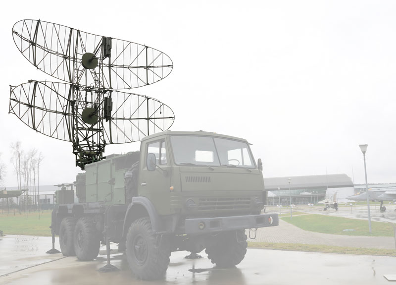 Six-wheel army truck with large double parabolic grid antenna deployed on top