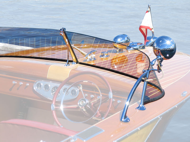 Close-up of a wooden runabout boat with custom railing and windshield