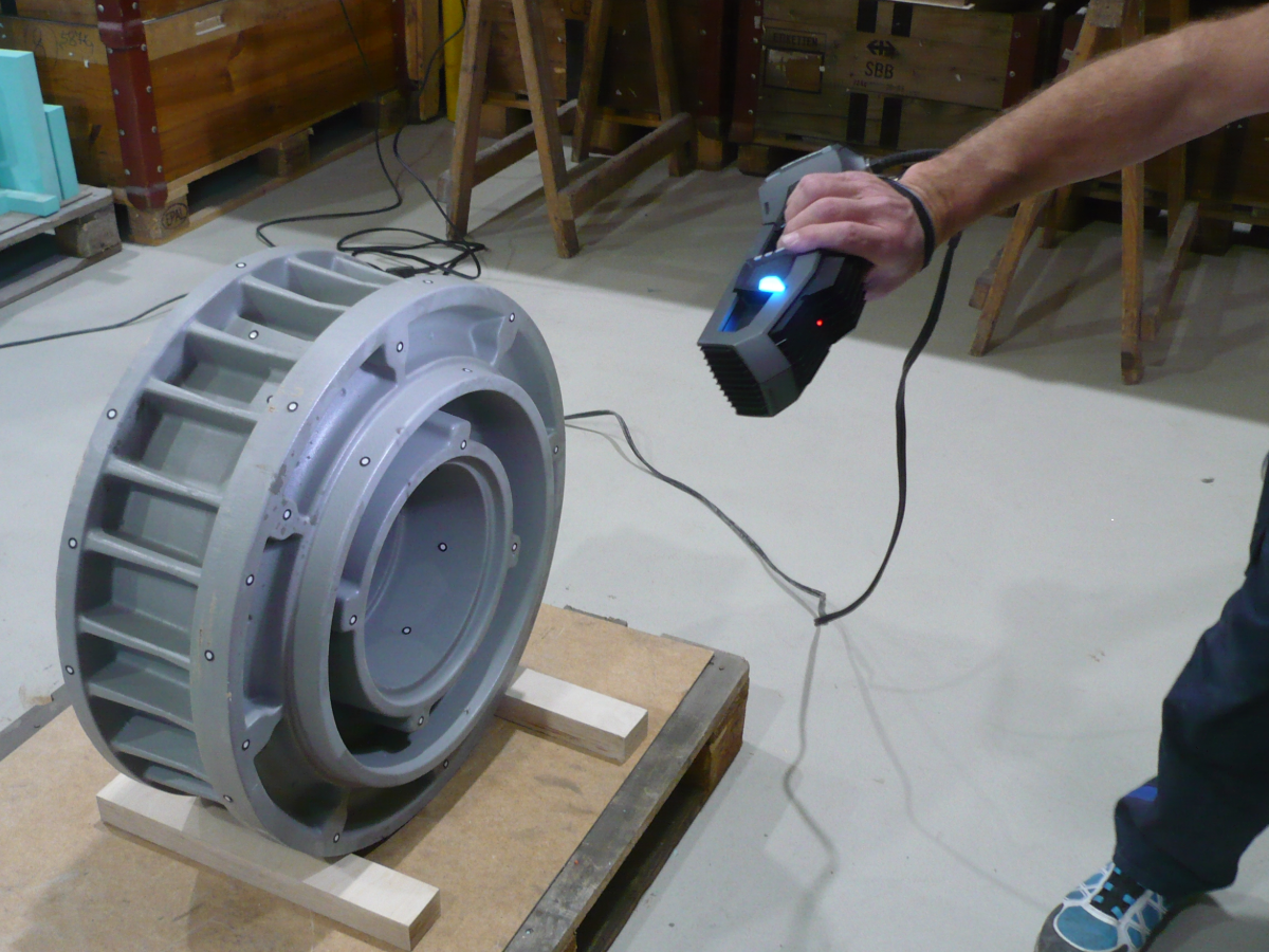 Man using a Go!SCAN 3D to measure an oil chamber casing on a palet.