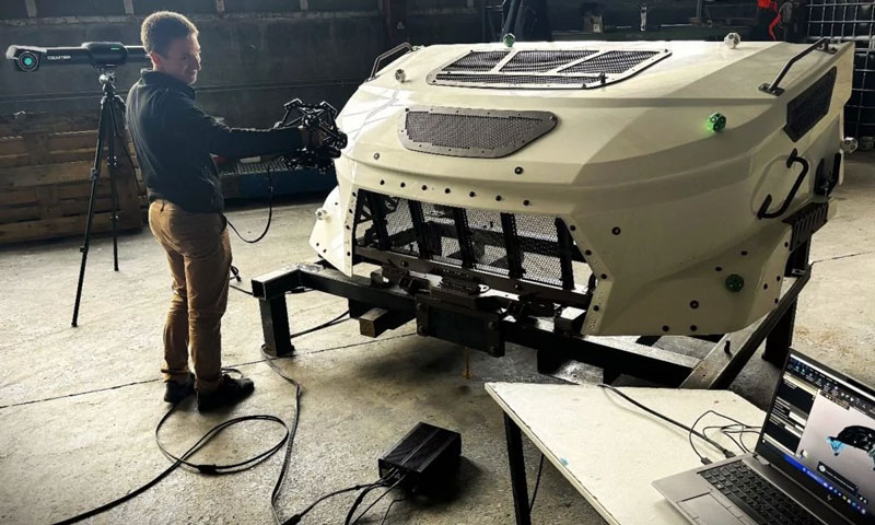 Team member using MetraSCAN 3D to scan a military vehicle hood