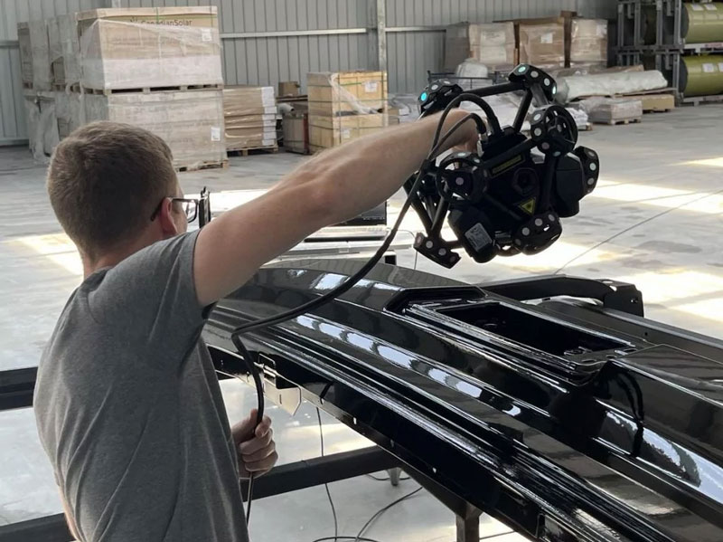 A team member using the MetraSCAN 3D to scan a large bus part.