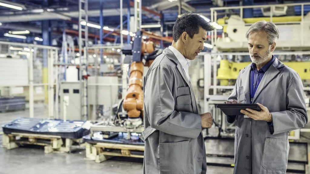 2 quality control managers discuss about their production assembly and check an inspection report