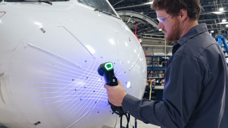 A picture of a Rapid3D technician using the HandySCAN 3D to assess the nose of a WestJet airplane.