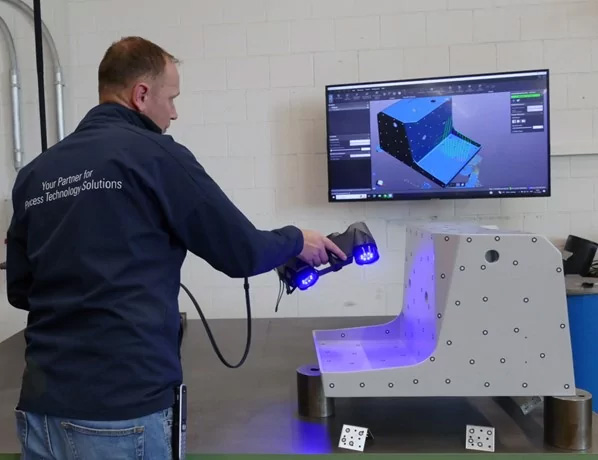 Engineer using the Creaform HandySCAN 3D|BLACK Series to scan a machine housing and looking at the 3D model on a computer screen.