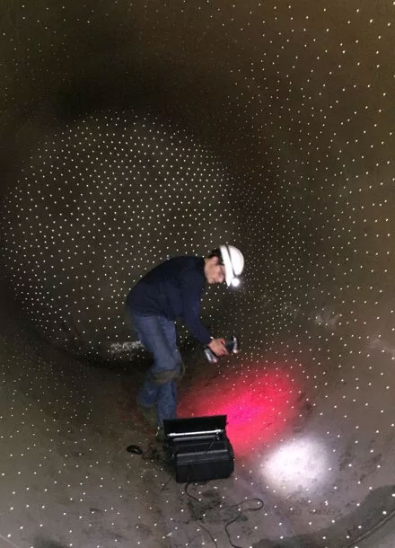 NDT technician scanning a cylindrical section inside a rail car with a multitude of targets positioned on the surface