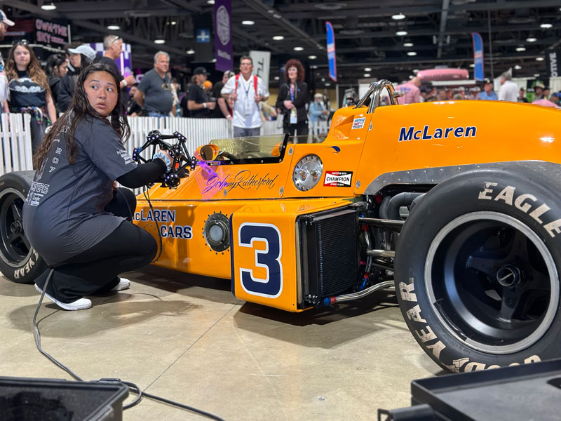 A student at the Hawthorne High School of Manufacturing & Engineering 3D scans an orange McLaren race car with the MetraSCAN BLACK+™|Elite.