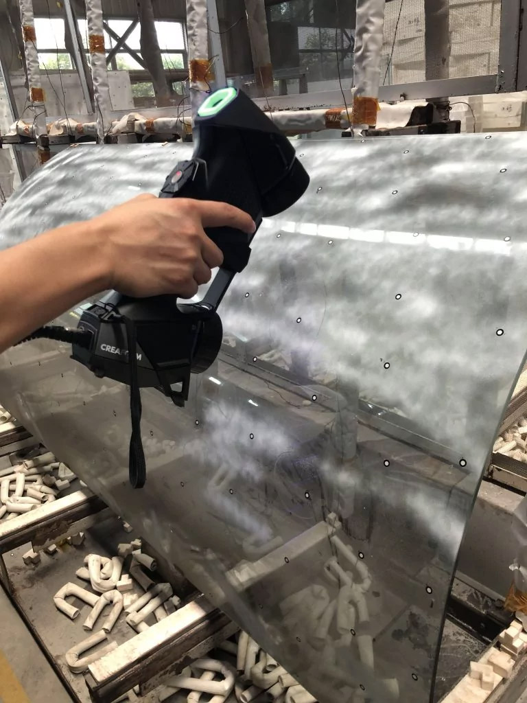 作業現場で曲面ガラス部品をHandySCAN 3D | BLACKシリーズスキャナーでスキャンしているところの近接写真