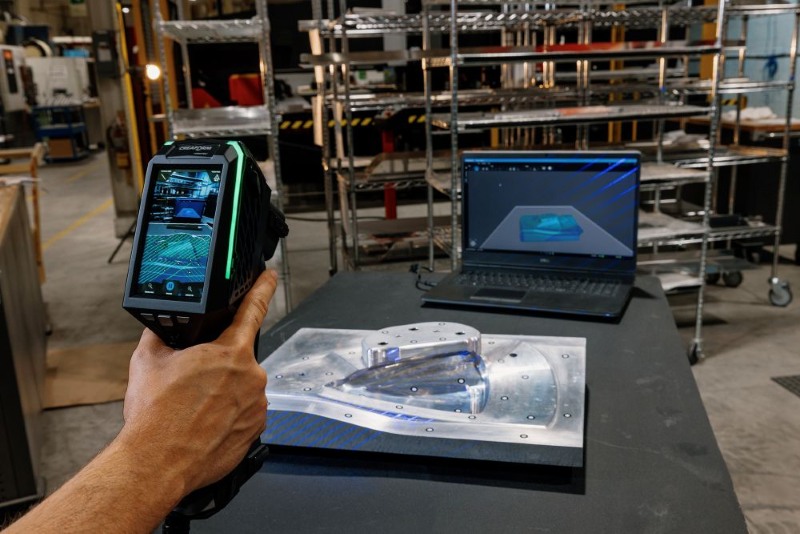 Eine Person bedient einen 3D-Scanner mit integriertem Display und betrachtet die Echtzeit-Visualisierung auf dem Bildschirm.