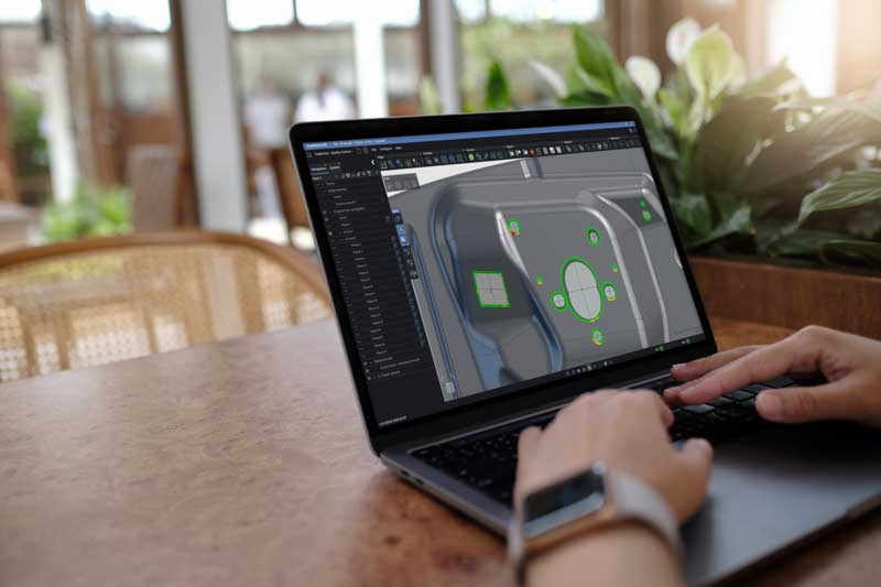 某人坐在桌前,使用笔记本电脑在 Creaform Metrology Suite 的检测模块中显示一个零件