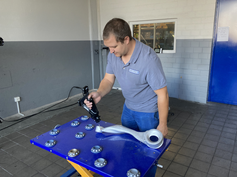 An employee uses the HandyPROBE portable optical CMM to capture 3D measurements of a metal component.