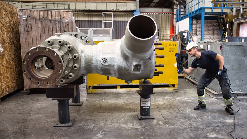 Employee wearing a hard hat using the HandySCAN 3D|MAX Series scanner to measure a large pipe connector.