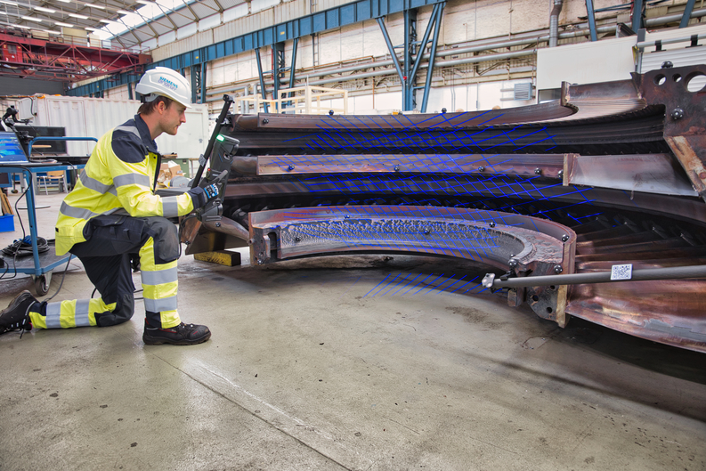 Employee wearing a hard hat using the HandySCAN 3D|MAX Series scanner to measure the interior of a very large turbine.