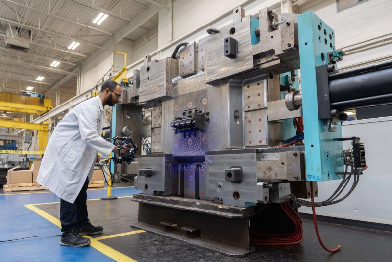 Quality control specialist using the MetraSCAN 3D scanner to inspect a large die shoe on the shop floor