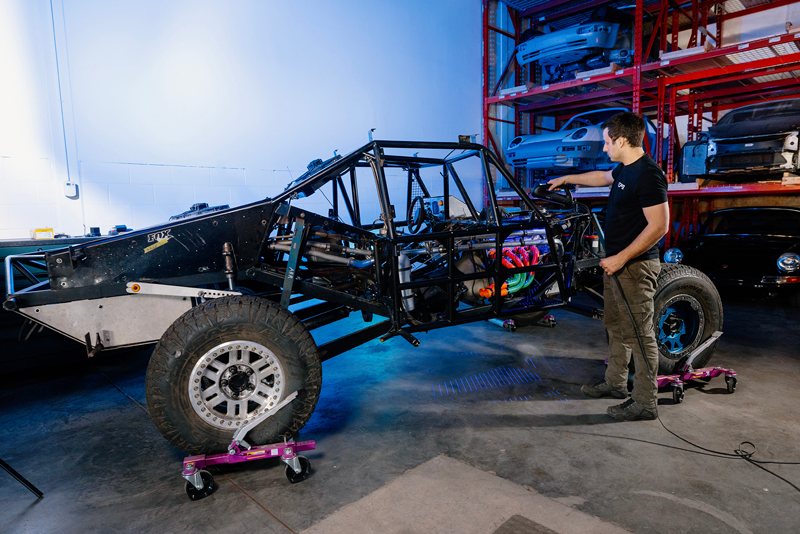 Un técnico de EP9 Autosport escaneando el chasis del coche de carreras con un HandySCAN 3D|Serie PRO de Creaform en el taller, capturando la geometría completa del vehículo.