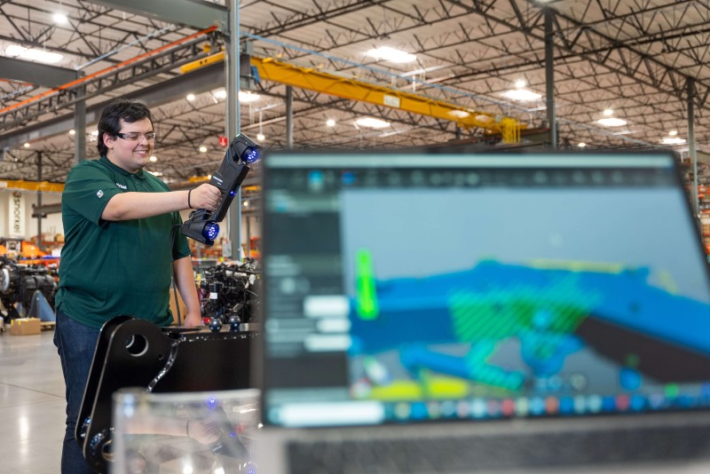 Tecnico felice di utilizzare la Serie MAX e la Creaform Metrology Suite per ispezionare parti di grandi dimensioni in un ambiente di produzione.