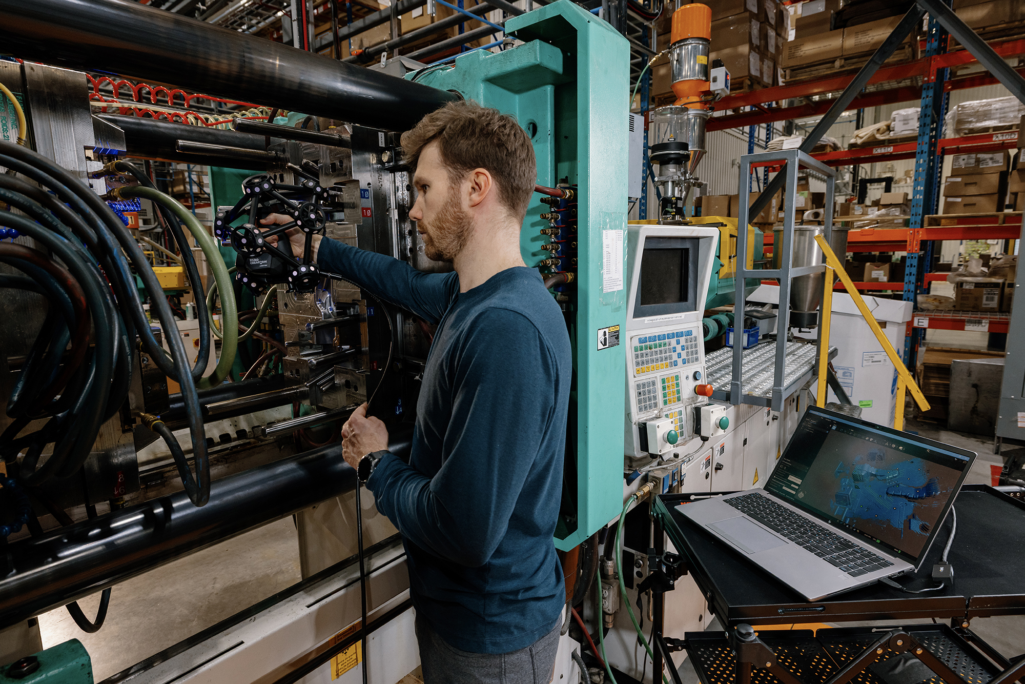 Alt-Text: Application Engineer, der einen MetraSCAN 3D-Scanner zur Prüfung einer Spritzgussform in einer Fertigungsumgebung einsetzt. 