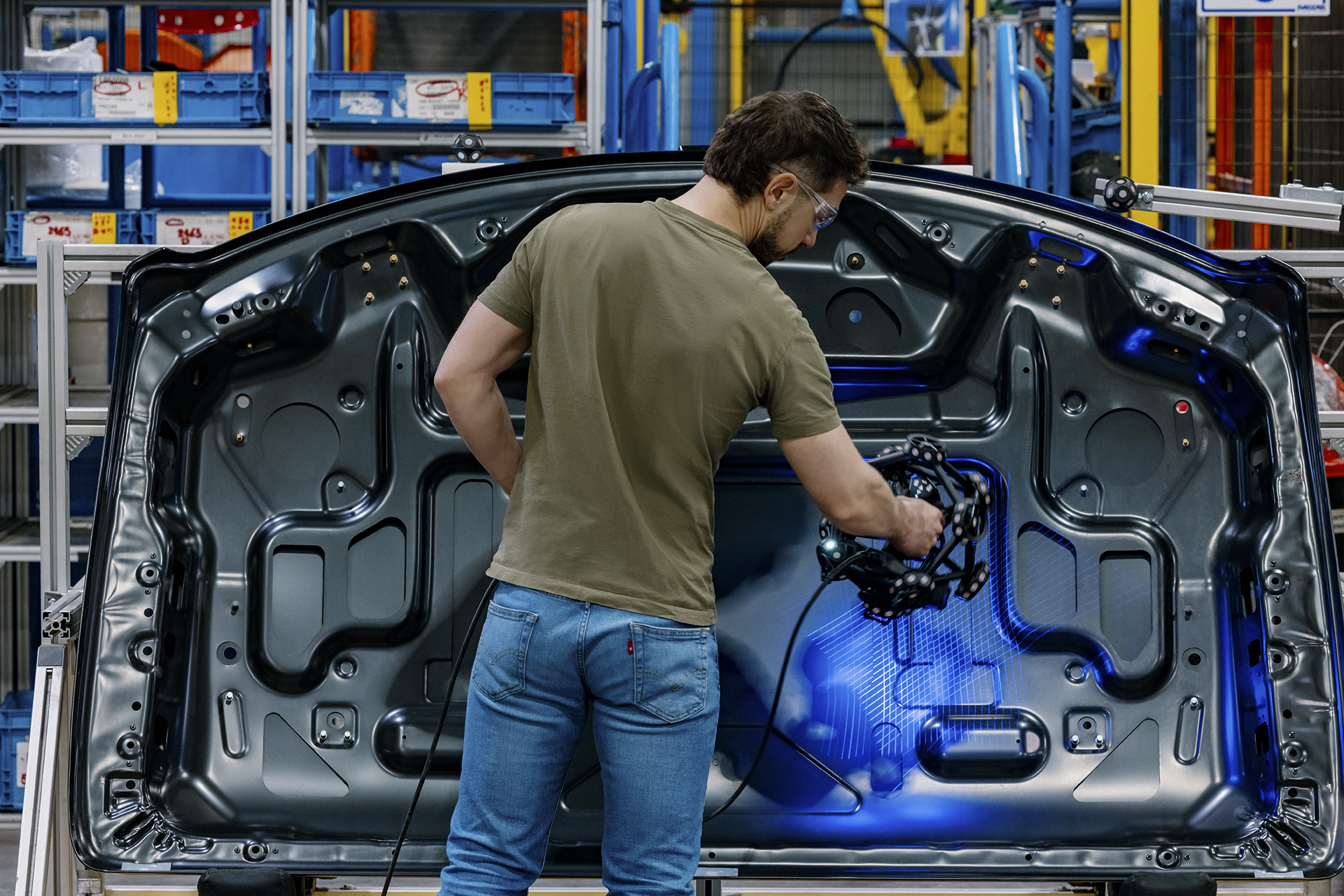 Portable 3D scanner capturing precise 3D data on a stamped vehicle hood panel for dimensional inspection on the shop floor. 
