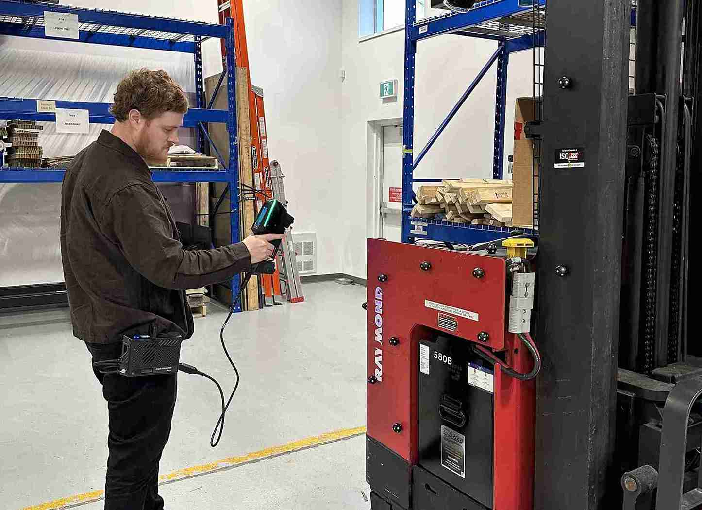 Employee in a warehouse using the HandySCAN EVO Elite with the Mobility Kit to scan a red and black forklift.