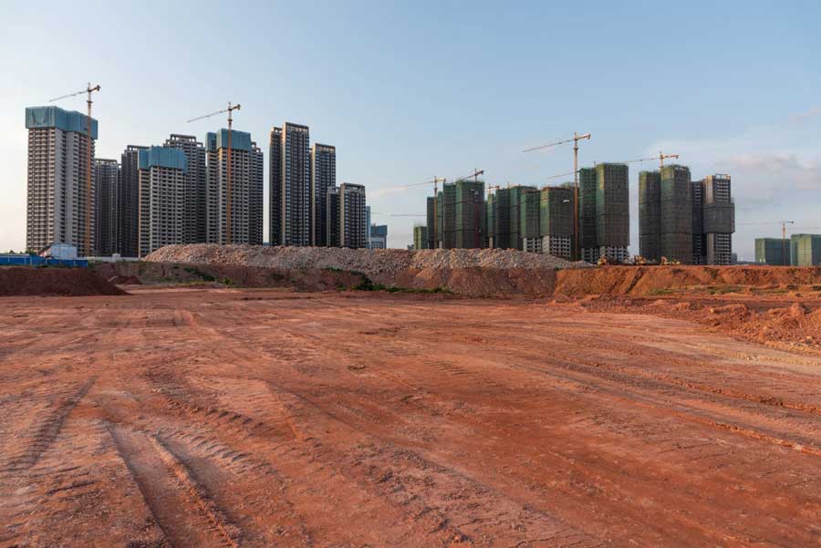 Varios edificios de gran altura rodeados de altas grúas amarillas con una gran obra de construcción en primer plano