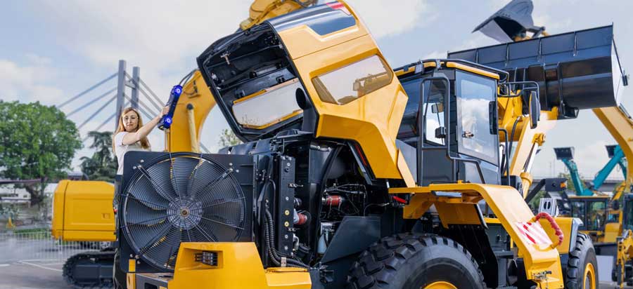 Woman using the HandySCAN MAX Series scanner to scan the interior of the hood of a yellow and black front loader