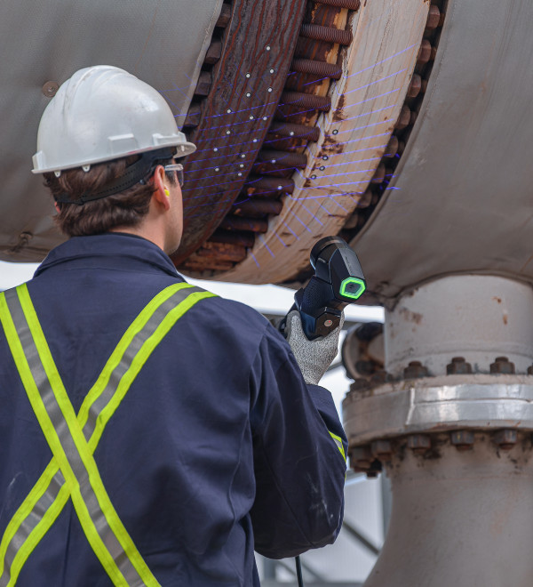 Worker in safety gear using a HandySCAN 3D portable scanner to inspect large industrial equipment