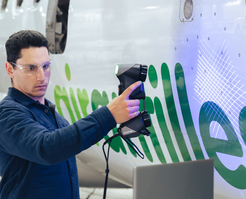 Person using a HandySCAN 3D EVO portable scanner to capture precise measurements on an aircraft fuselage
