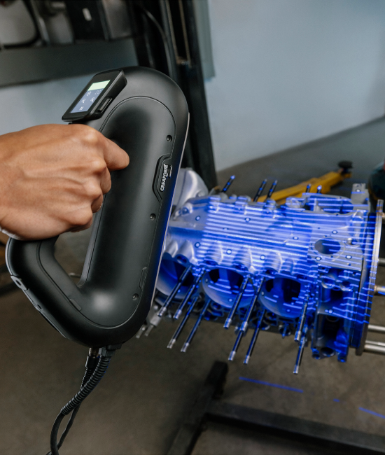  PRO Series 3D scanner projecting blue laser lines onto a complex metal engine component
