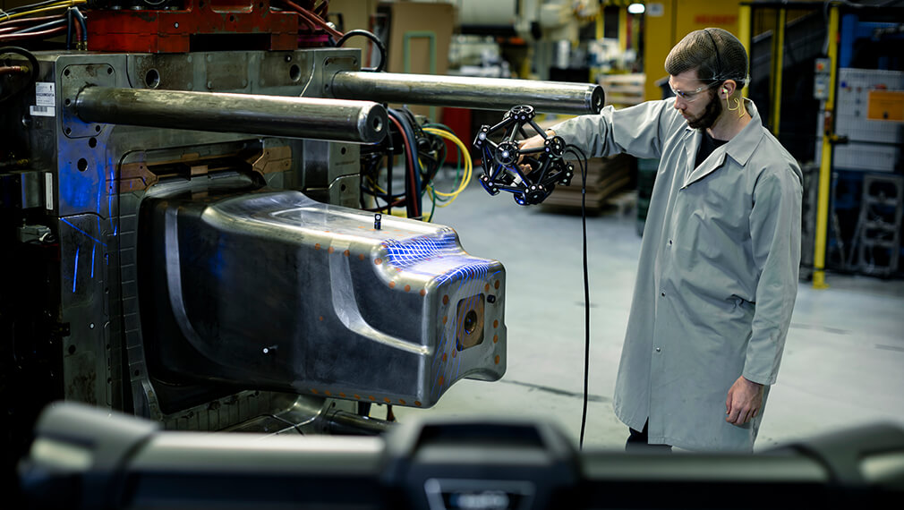 Technician in a manufacturing facility using a Creaform MetraSCAN 3D scanner to perform precise surface inspections on a large industrial mold.