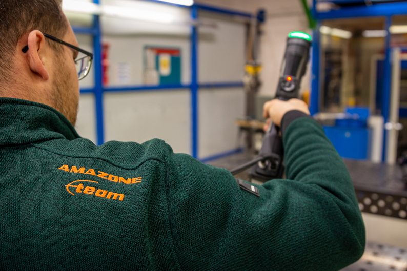 Un ingénieur qui porte un pull Amazone numérise une pièce avec des scanners 3D Creaform de classe métrologique.