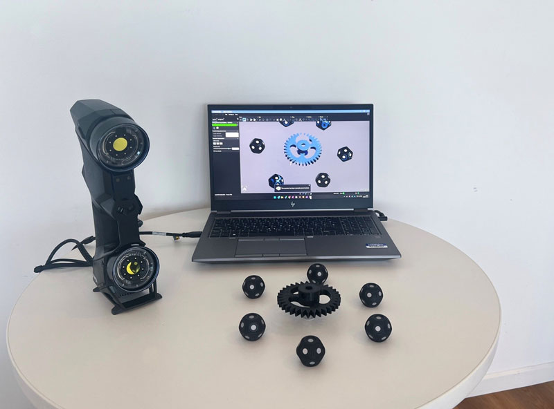 L’engrenage complet imprimé en 3D sur une table à côté de cibles à 360°, du HandySCAN BLACK+|Elite et d’un ordinateur portable qui affiche le module Numérisation vers CAO Pro.