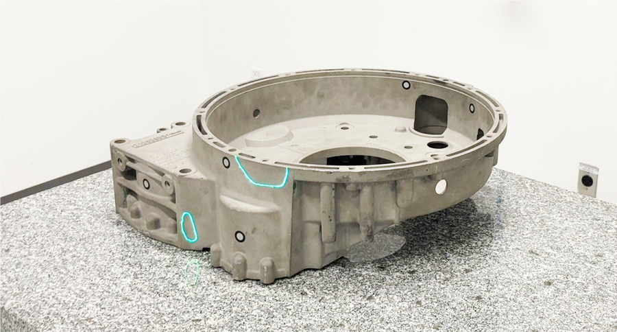 Casted gearbox on a table with projected lasers on the parts that requires rework