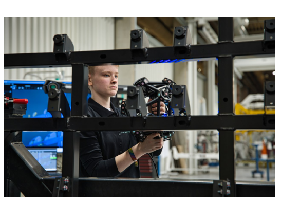 HOLON engineer using a portable MetraSCAN 3D to capture 3D data of a vehicle frame structure during large-part inspection.