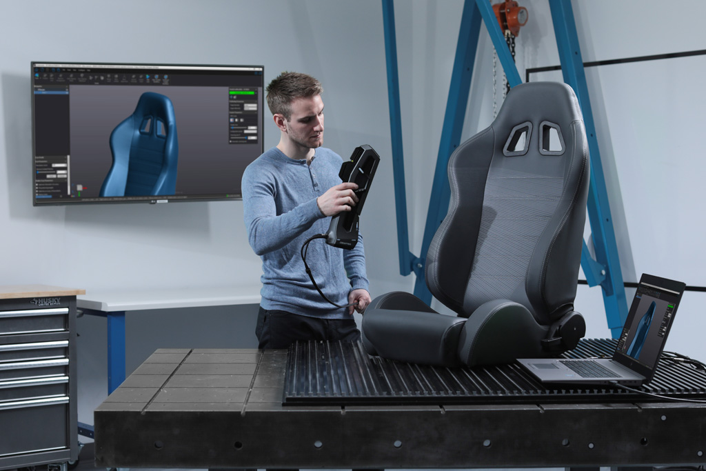 A white light structured light handheld 3D measurement system scanning a leather car seat in a metrology lab 