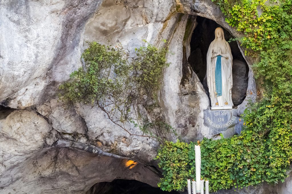 La statue emblématique de Notre-Dame de Lourdes est nichée au-dessus de la grotte sacrée de Massabielle