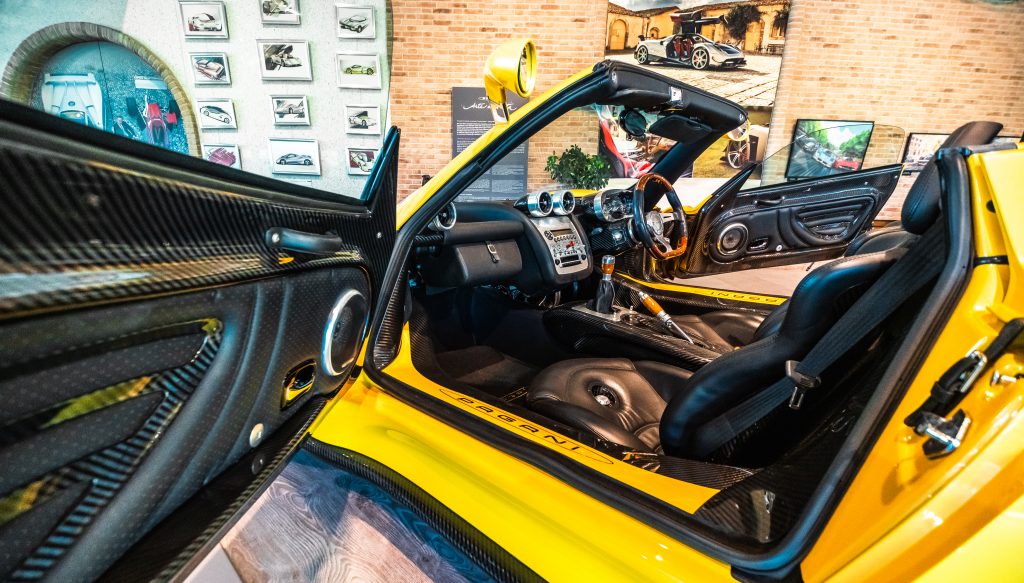 Interior of a yellow Pagani Zonda F Roadster in front of a wall with several pictures inside the Pagani Museum