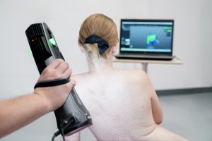 The artist in the nude being scanned by a technician with a Go!SCAN SPARK with a laptop in the background