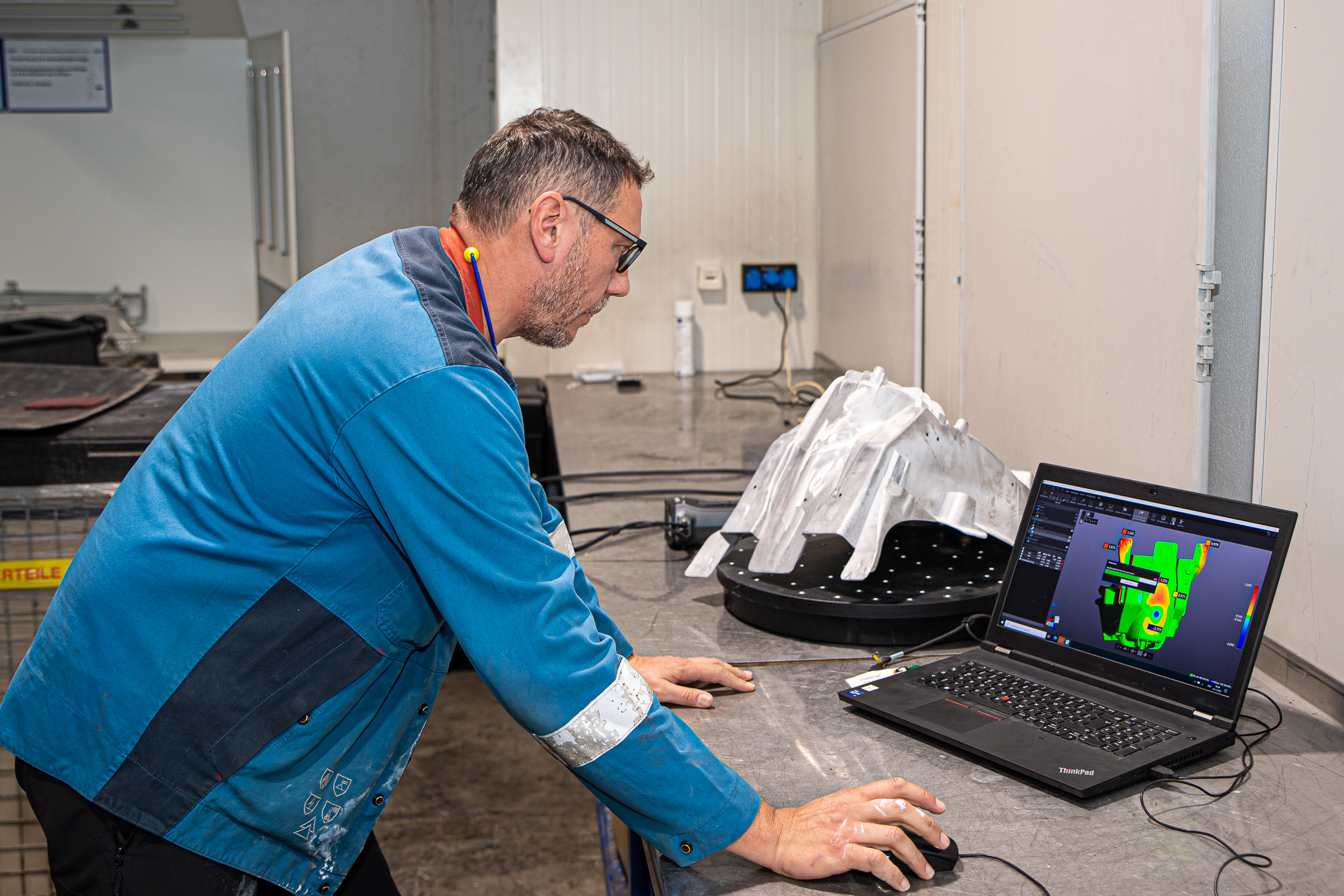 Un empleado de GF Casting observa el componente escaneado del software VXinspect en una computadora portátil. Se puede ver una comparación de CAD con el mapa de colores.