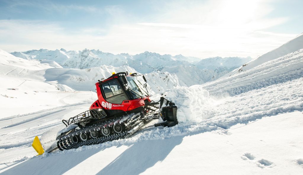 PistenBully 600 red snow groomer going up a snow slope