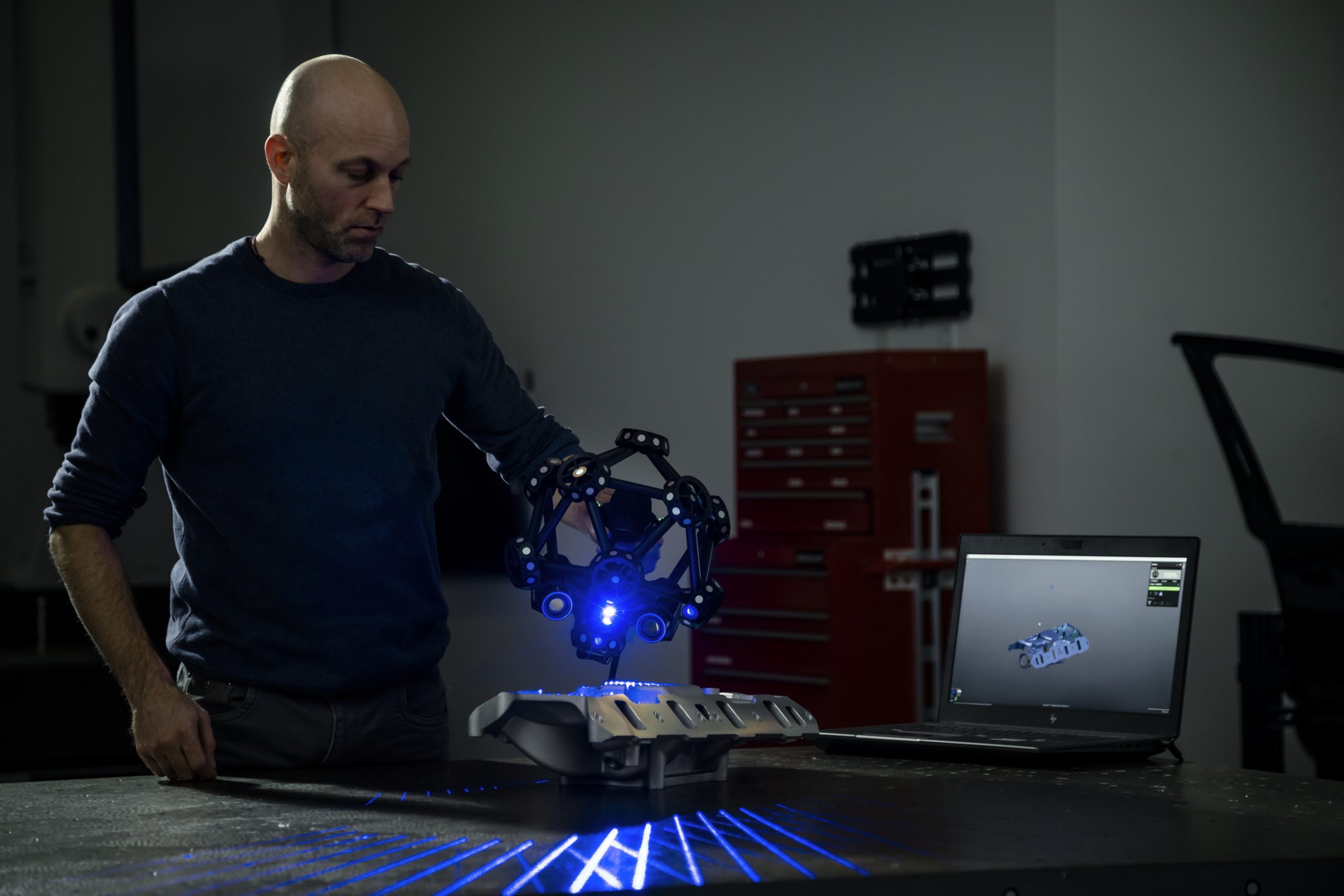 Uma pessoa realiza a digitalização de uma peça usando um escâner MetraSCAN 3D. 