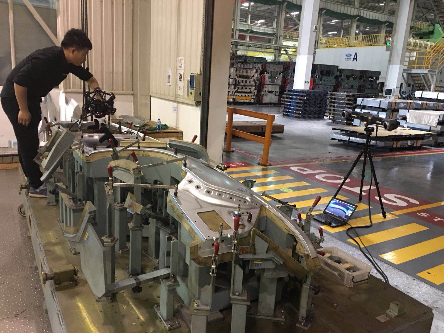 Um trabalhador digitaliza uma chapa de metal em um gabarito com o escâner MetraSCAN 3D e o C-Track.