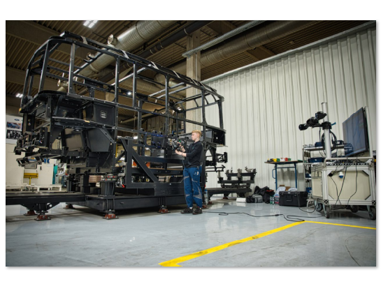 HOLON-Techniker im Produktionsbereich bei der Durchführung von 3D-Messungen an einem in Originalgröße gefertigten Fahrzeugchassis; die angewendete Messtechniklösung ist der MetraSCAN 3D mit C-Track.