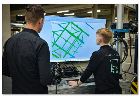 HOLON engineer and Creaform technician reviewing 3D measurement data of a vehicle frame with the PolyWorks software ecosystem during an inspection workflow on the shop floor.