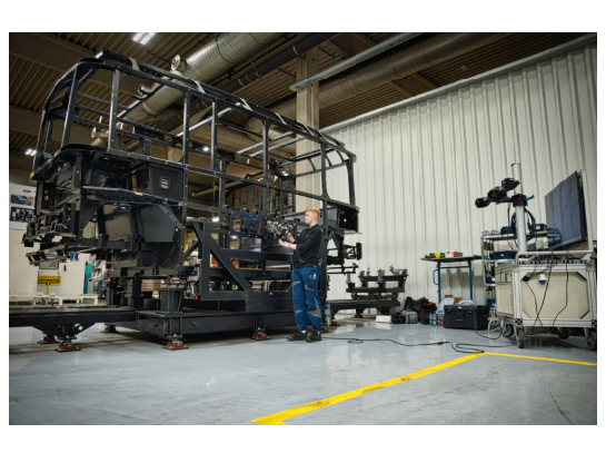 Un technicien de HOLON effectuant des mesures 3D sur une structure de châssis de véhicule à taille réelle dans un atelier de production à l’aide d’un système MetraSCAN 3D avec C-Track.