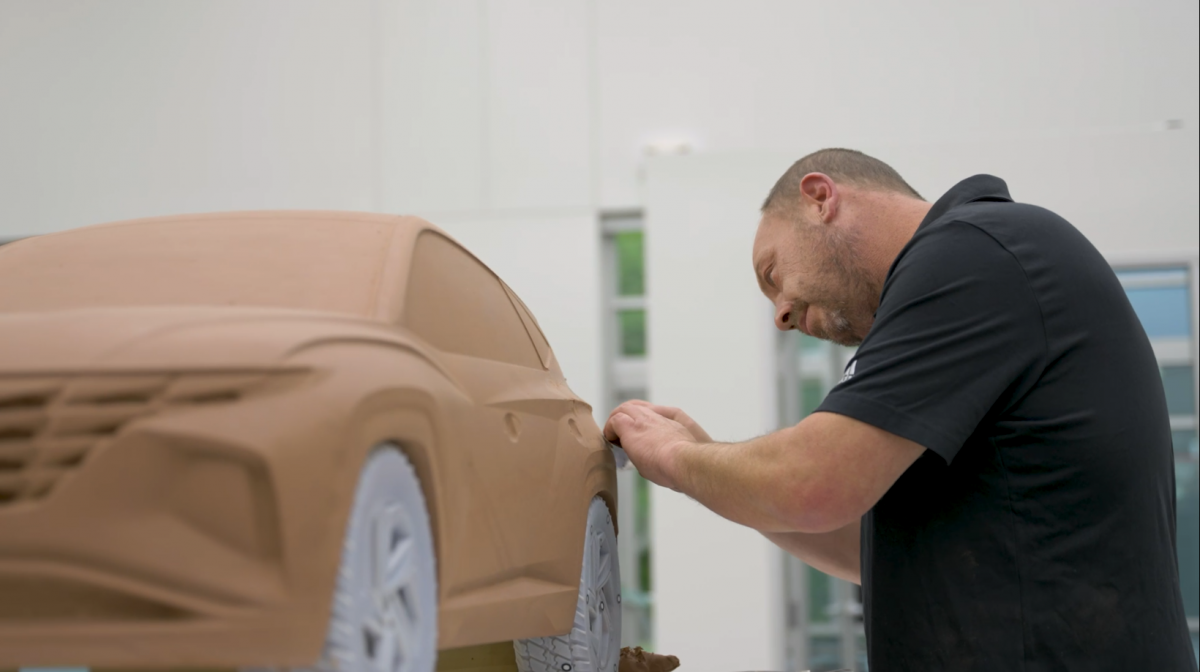 Employee working on the scaled down clay model of the car